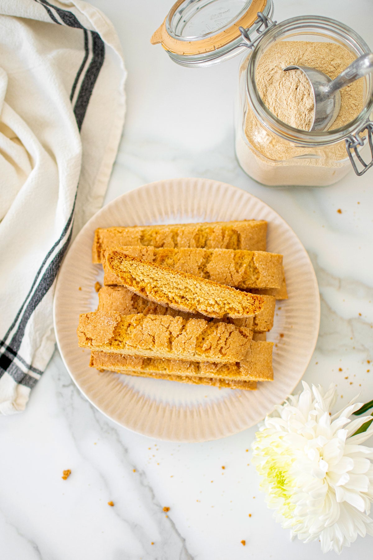 kamut flour biscotti on a plage on a white marble counter with fresh flowers.