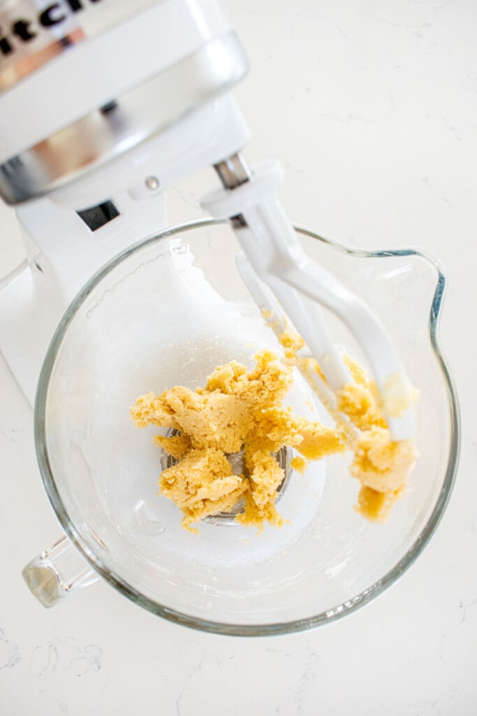 creamed butter and sugar in a glass mixing bowl on a white marble counter.