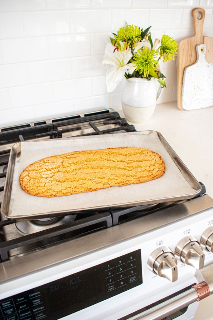 kamut flour biscotti log cooling on a baking sheet on an oven.