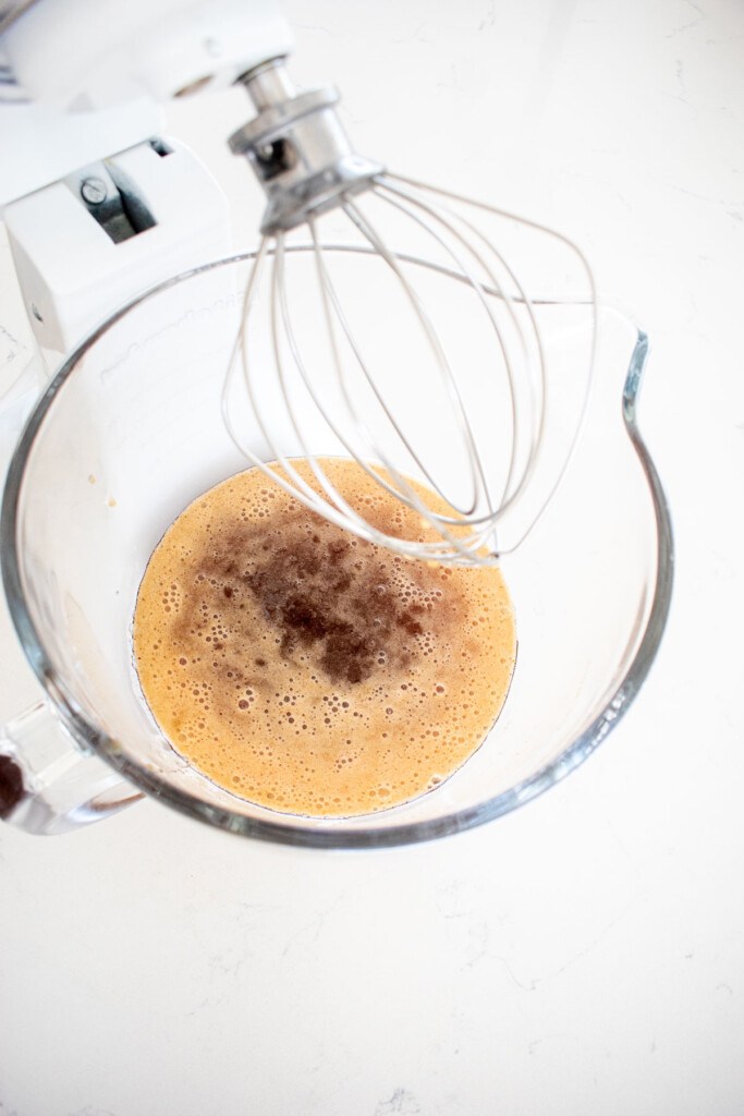 homemade pumpkin spice marshmallows being made in a stand mixer on a marble countertop.