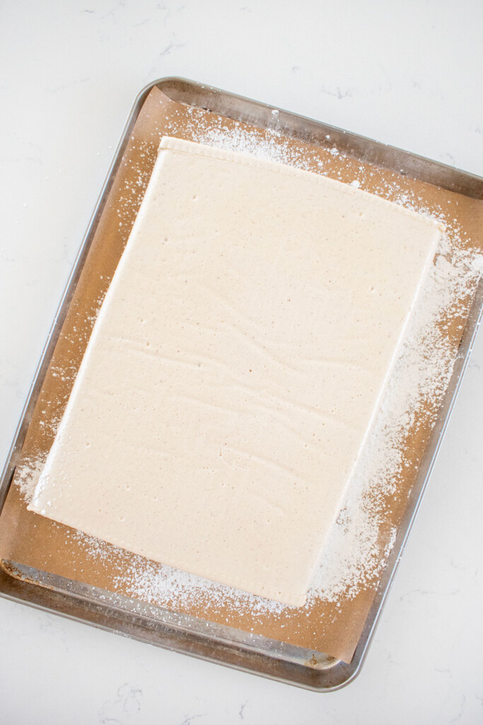 homemade pumpkin spice marshmallows on a baking sheet on a marble countertop.