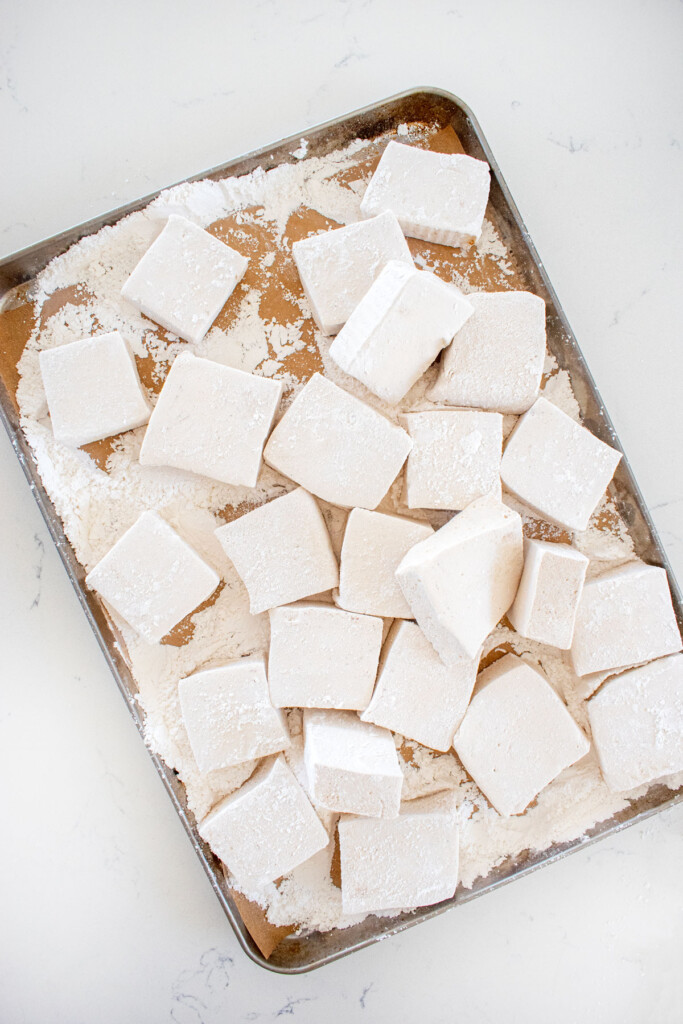 homemade pumpkin spice marshmallows cut into squares on a baking sheet on a marble countertop.