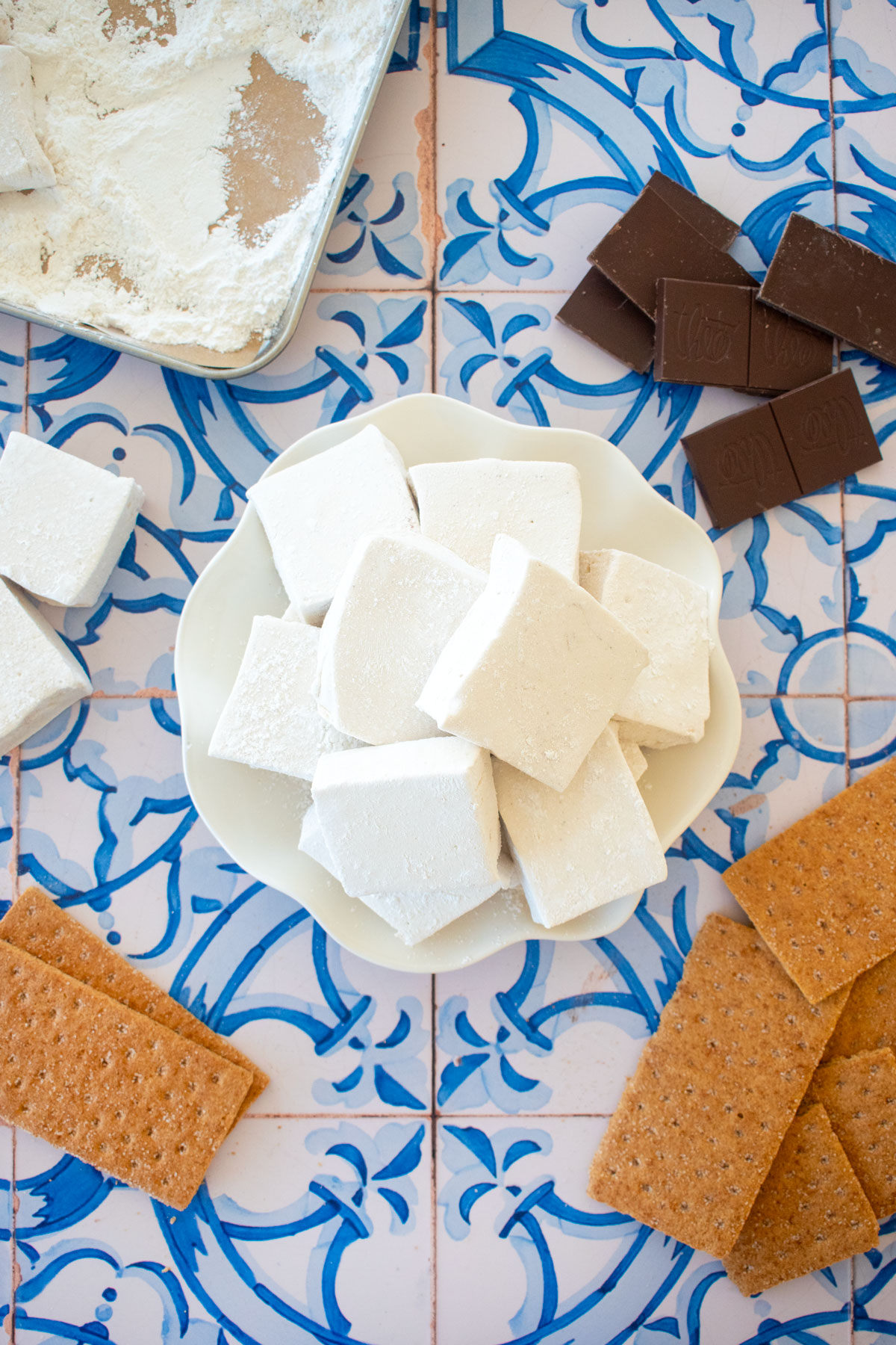 homemade pumpkin spice marshmallows without corn syrup on a plate with smores ingredients around.