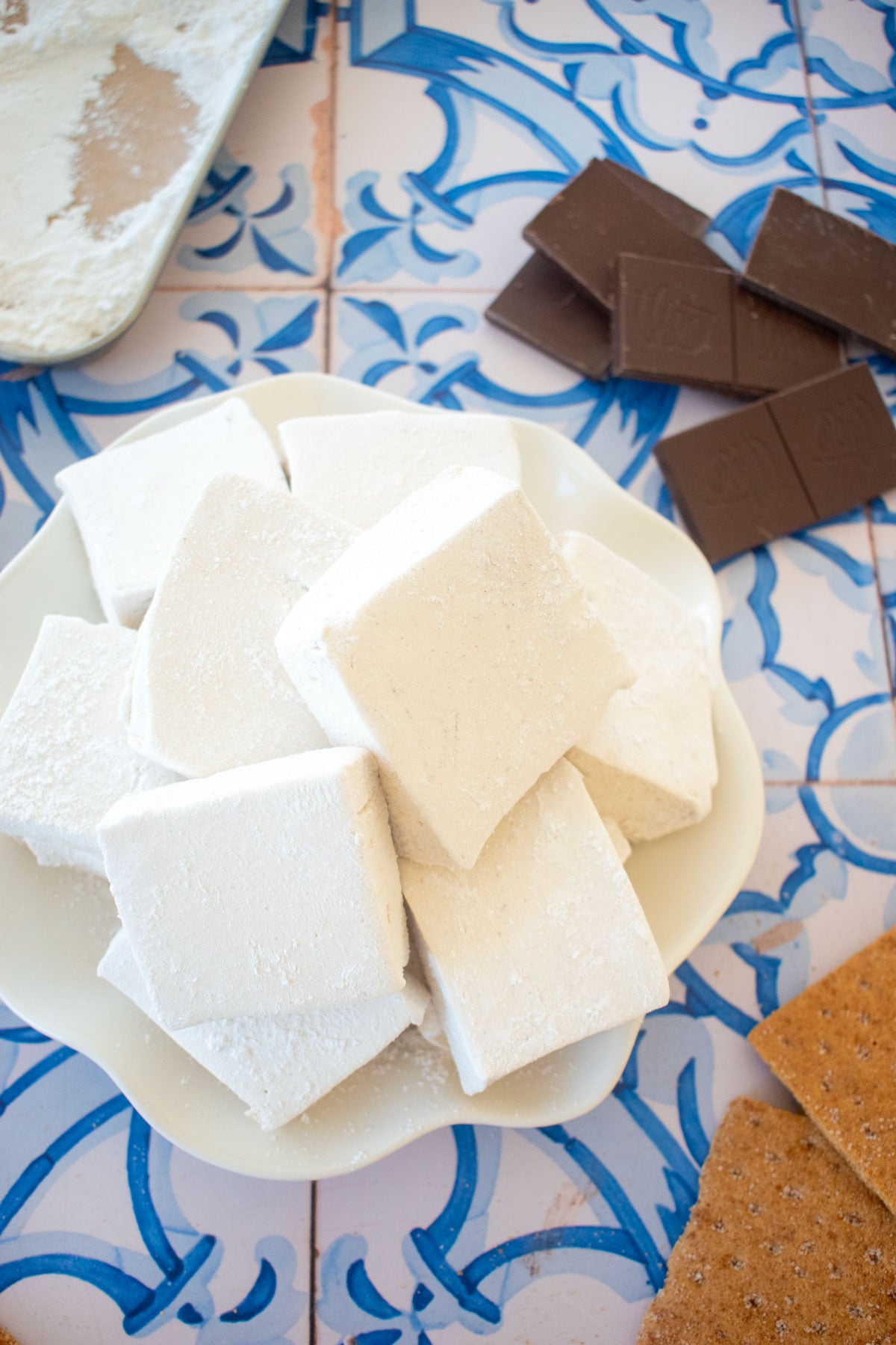 homemade pumpkin spice marshmallows without corn syrup on a plate with smores ingredients around.