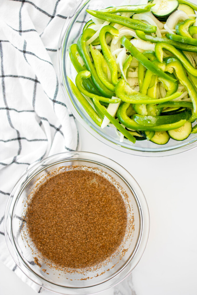 veggies in a glass bowl and pickling juice in a glass bowl on a white marble countertop.