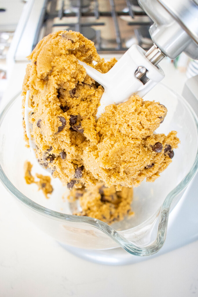 rye chocolate chip cookie dough in a glass mixing bowl on a white marble counter.