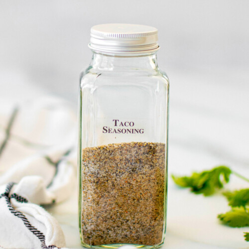 organic homemade taco seasoning in a spice jar on a marble counter with cilantro.