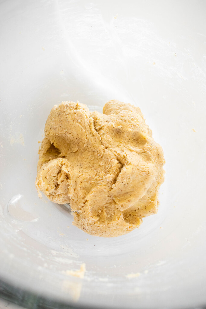 mixed vanilla bean pie crust in a glass mixing bowl on a white marble counter.