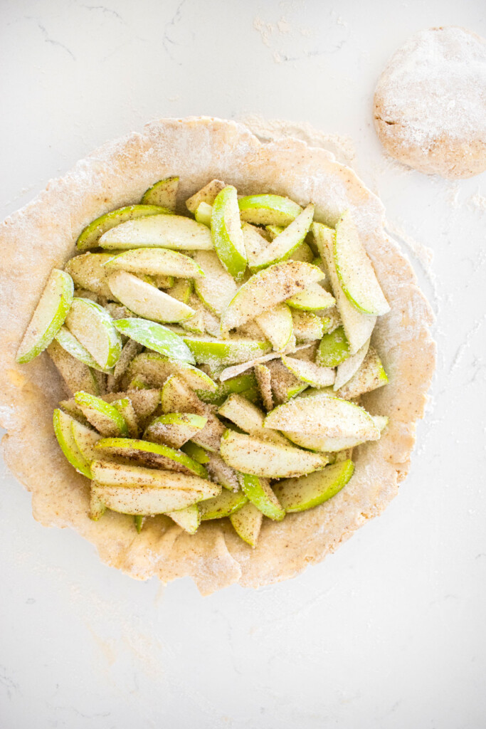 vanilla bean apple pie filling in a pie pan on a white marble counter.