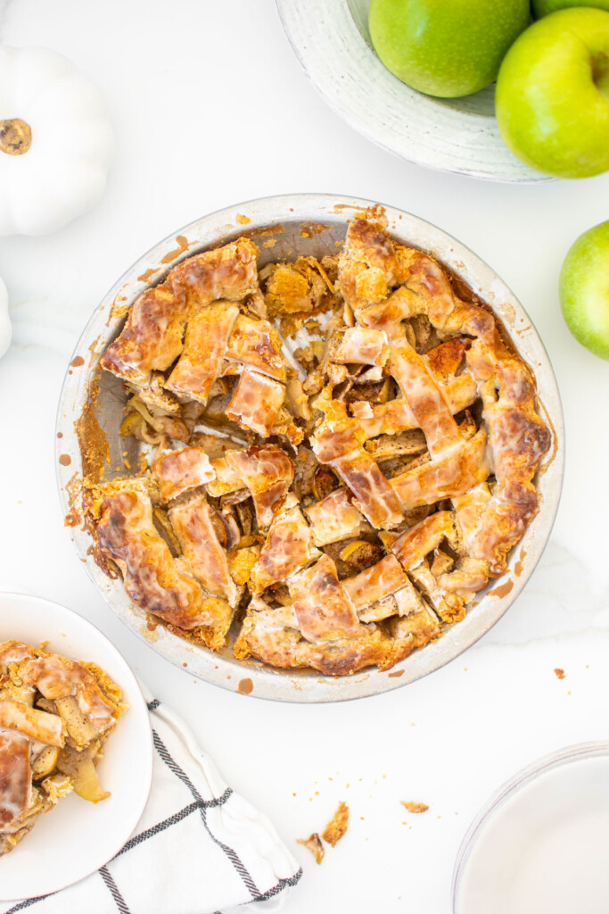 vanilla bean apple pie cut into slices on a white marble counter.