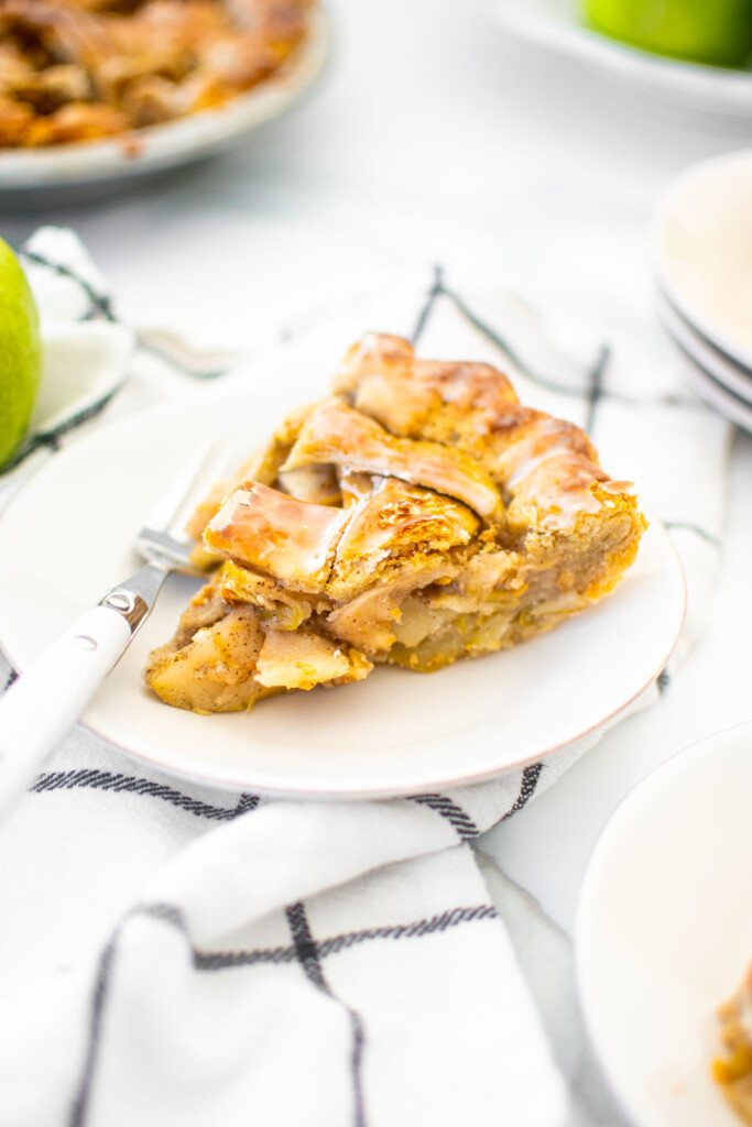 vanilla bean apple pie slice on a white plate on a marble counter.