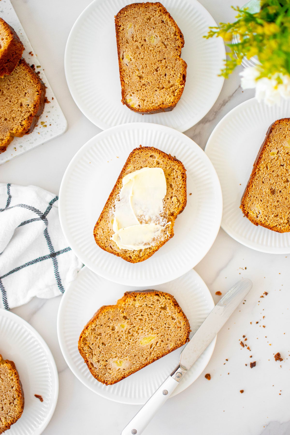 almond butter banana bread slices on on small plates on a white marble counter.