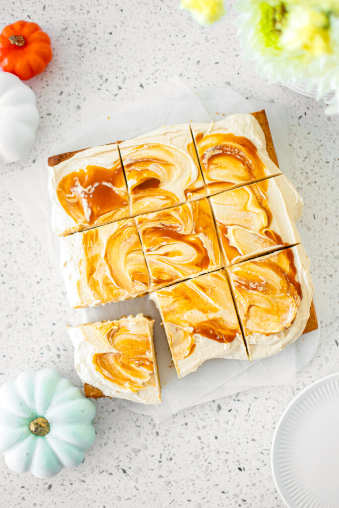 caramel pumpkin spice snack cake cut into square slices on a white marble counter.
