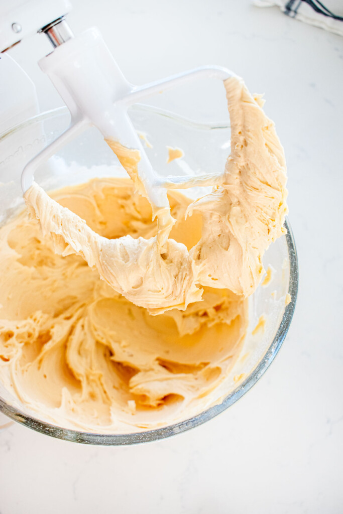 glass mixing bowl with fluffy caramel buttercream frosting inside.