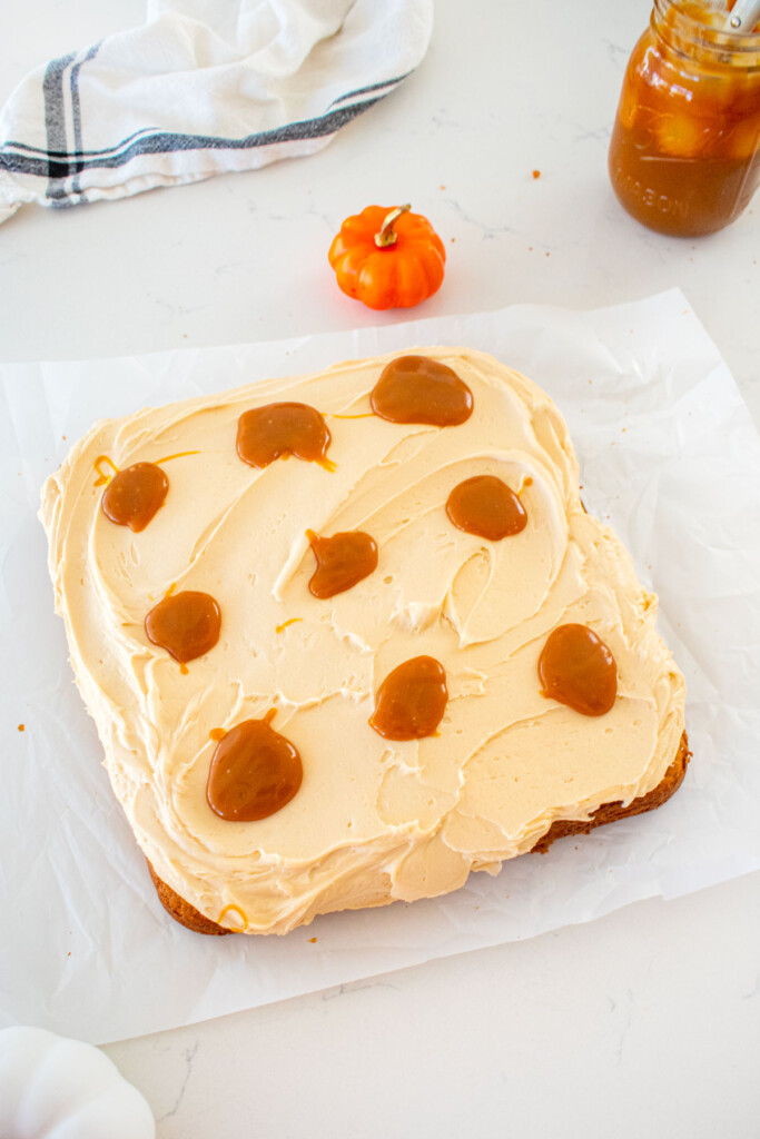 pumpkin spice snack cake with caramel frosting and small dollops of caramel in rows sitting on a marble counter.