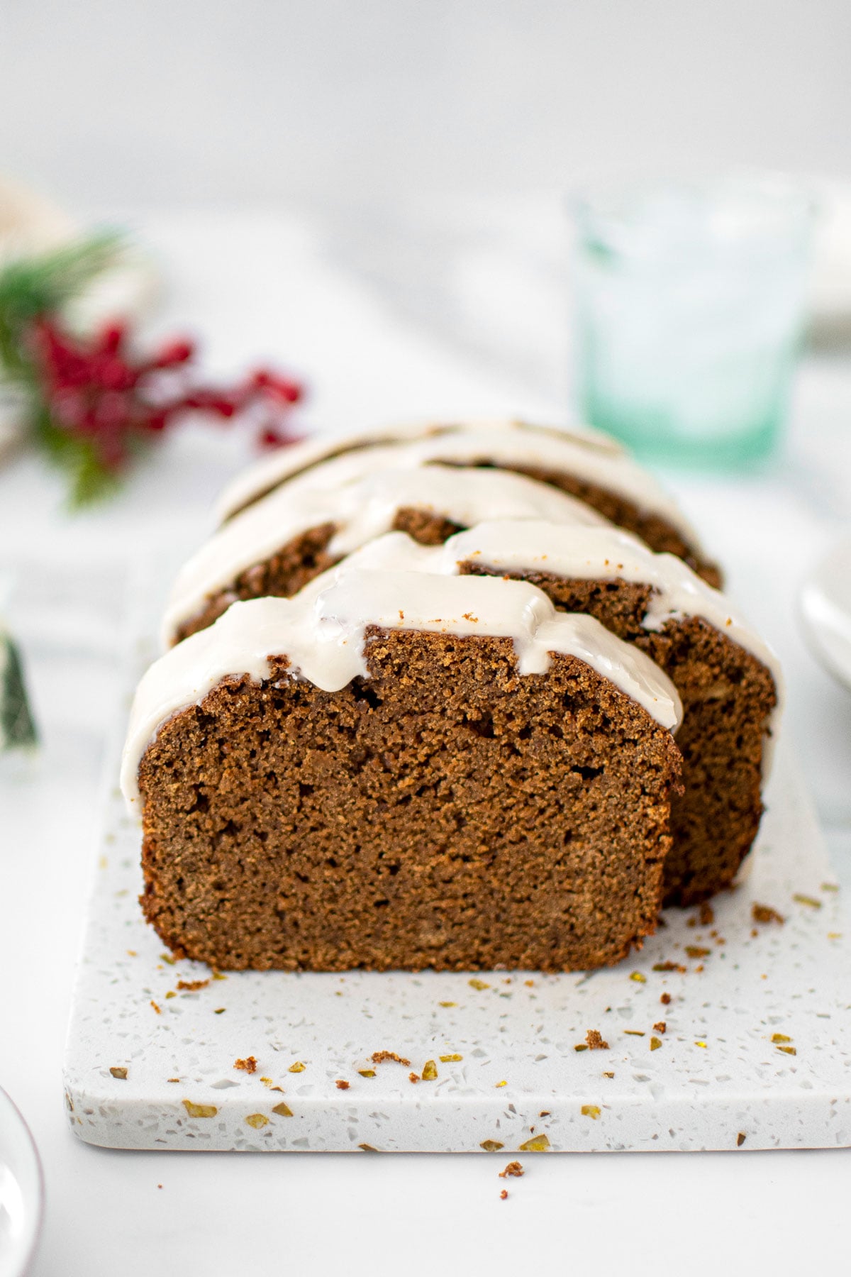 gingerbread banana bread with frosting cut into slices on a marble board.
