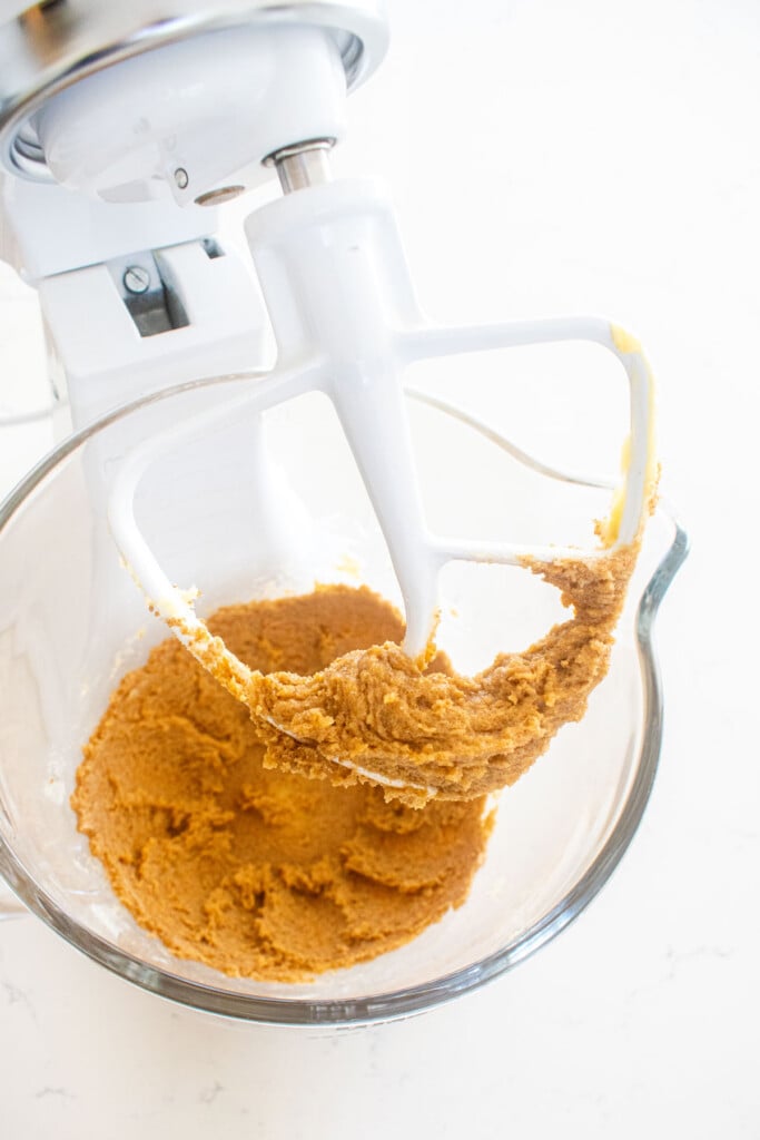 creamed butter and sugar in a glass mixing bowl on a white marble counter.