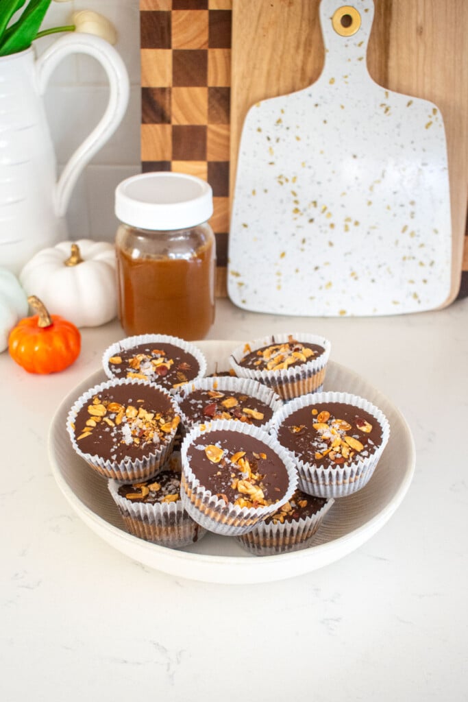 bowl of healthy chocolate peanut butter cups on a marble island counter with small pupmkins.