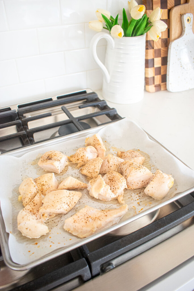 cooked chicken breast on a baking sheet cooling on top of an oven.