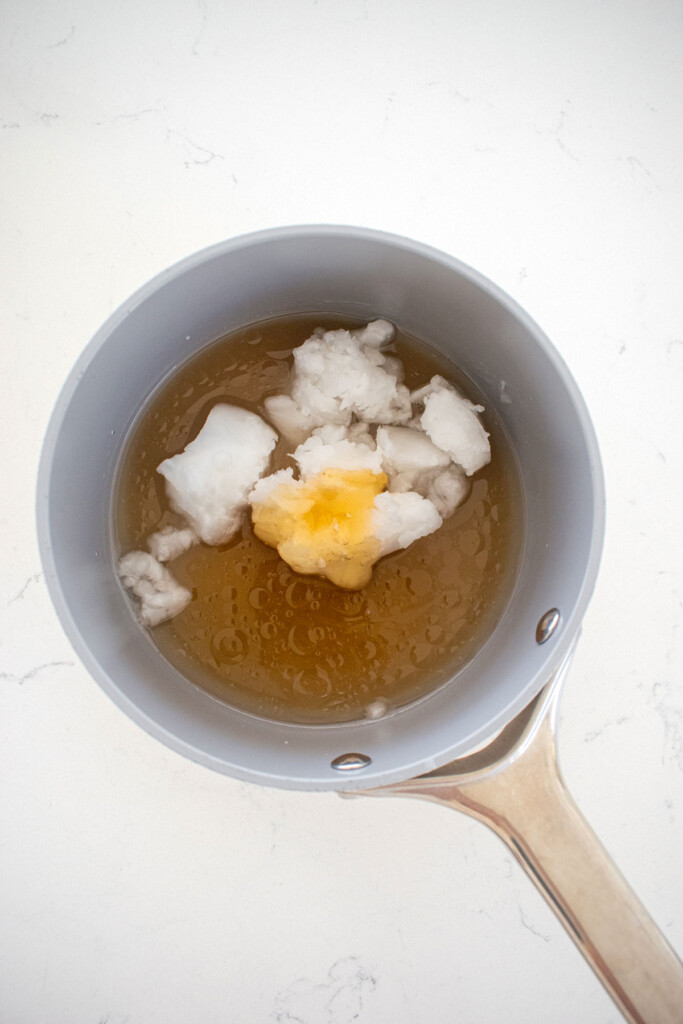 wet ingredients for homemade vanilla granola in a small pot on a white marble counter.