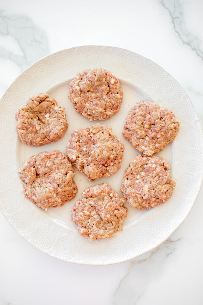 pork breakfast sausage patties on a plate on a white marble counter.