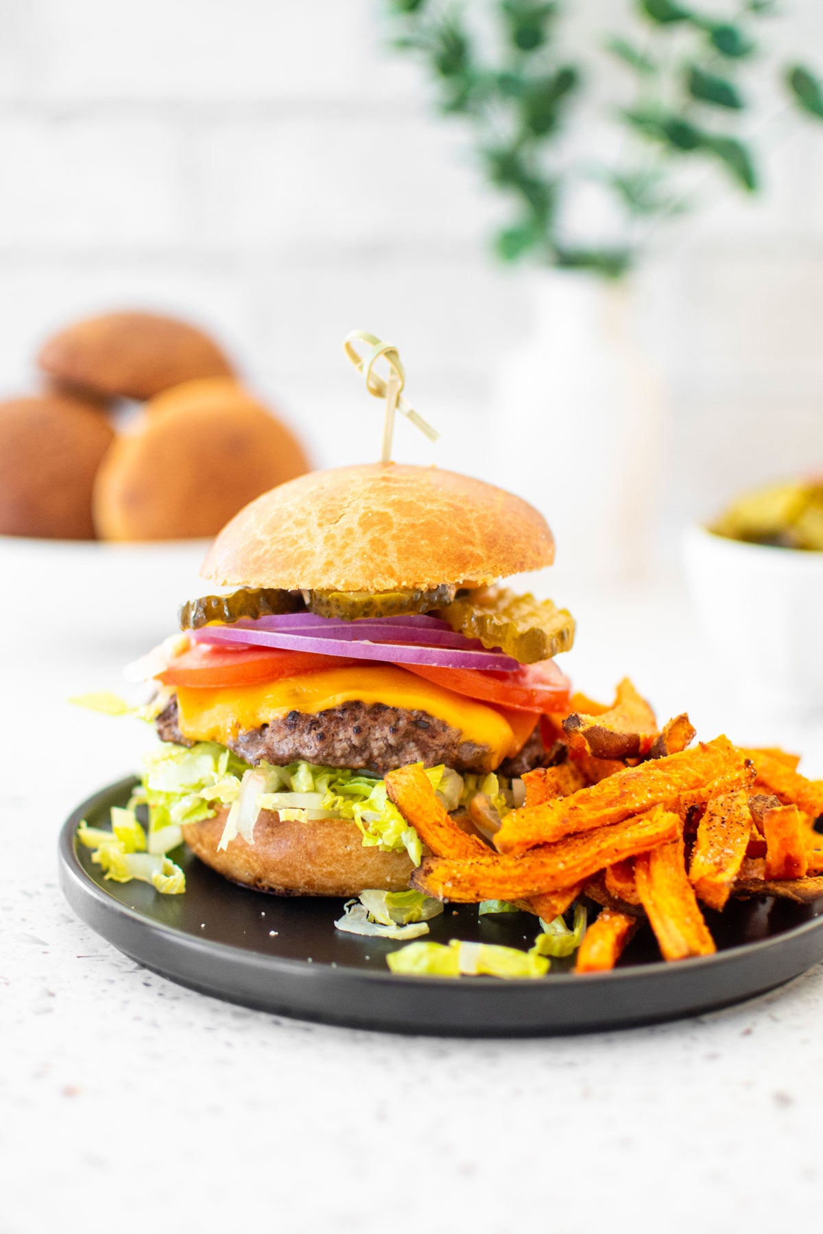 cheeseburger with pumpkin spice sweet potato fries on a plate on a white stone countertop.