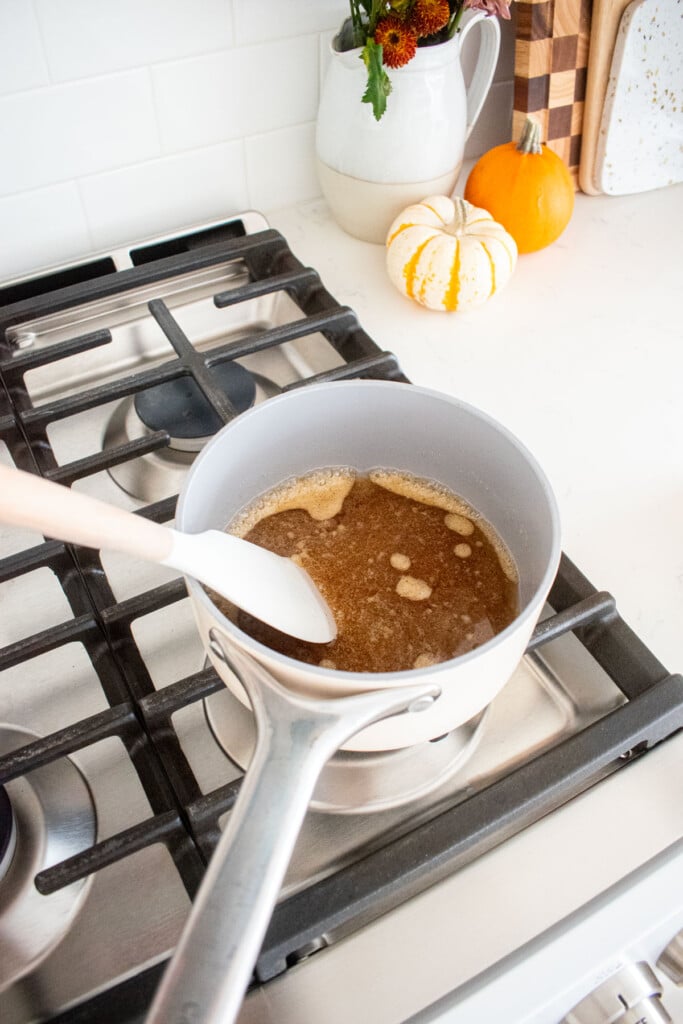 small pot on a stovetop being heated with wet ingredients for vanilla granola.