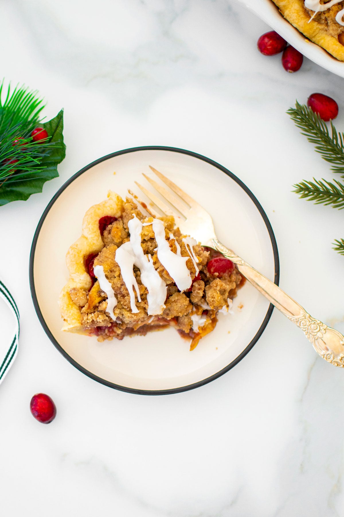slice of chinese five spice cranberry apple pie on a plate on a white marble counter.