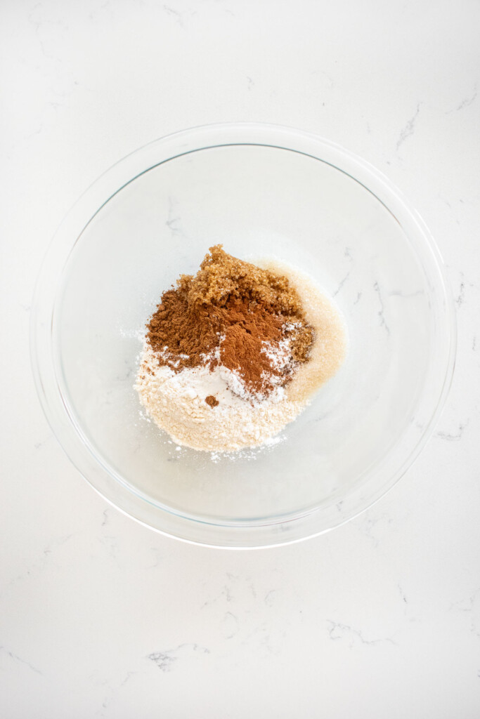 filling ingredients for chinese five spice cranberry apple pin a glass mixing bowl on a white marble counter..