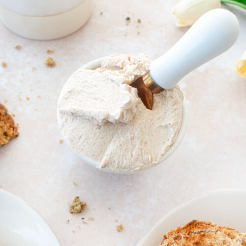 cinnamon honey cream cheese spread in a small bowl with a serving knife on a tan countertop.