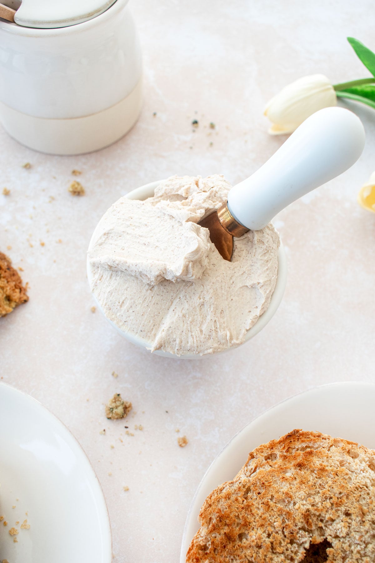 cinnamon honey cream cheese spread in a small bowl with a serving knife on a tan countertop.