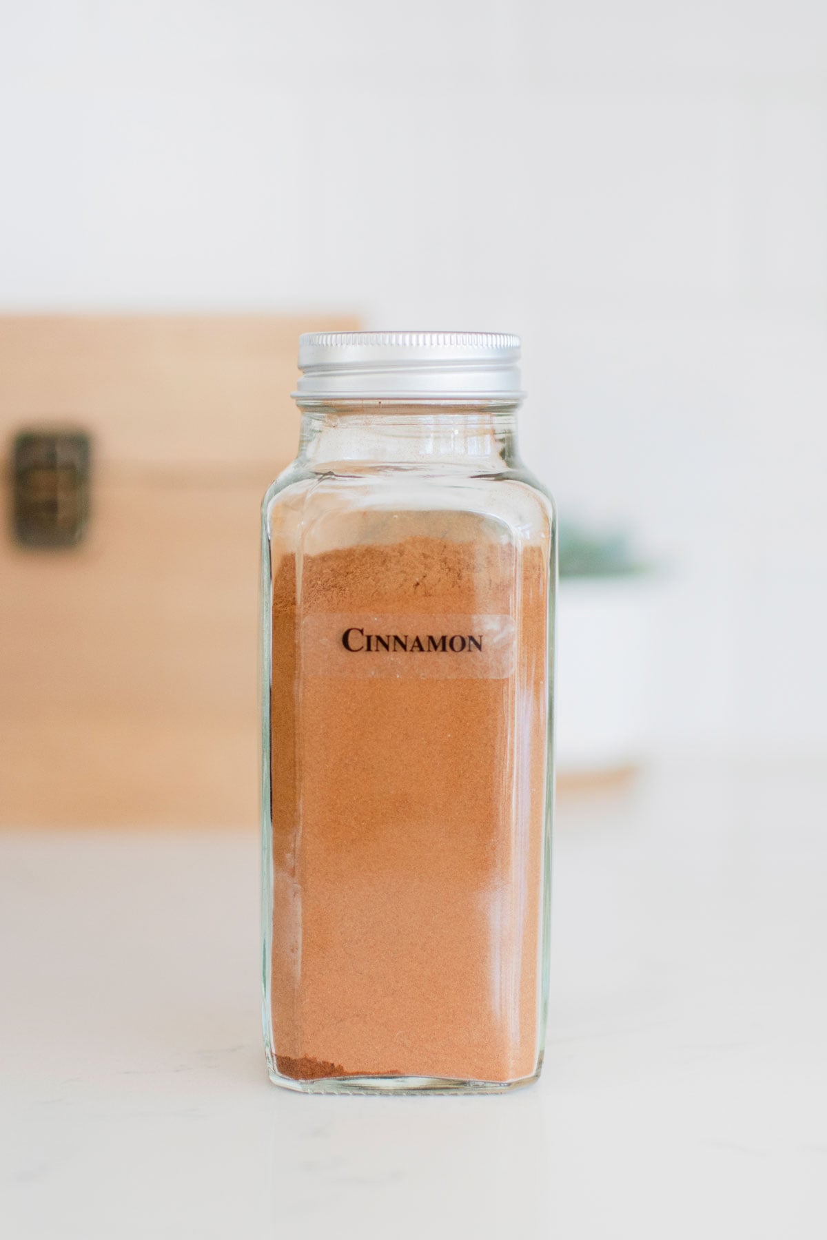 spice jar of cinnamon on a white marble counter.