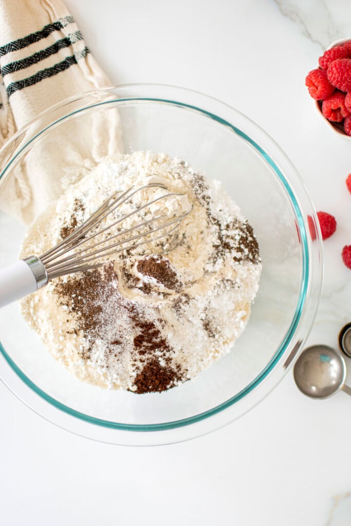 glass mixing bowl with homemade pancake mix being whisked together on a marble counter.