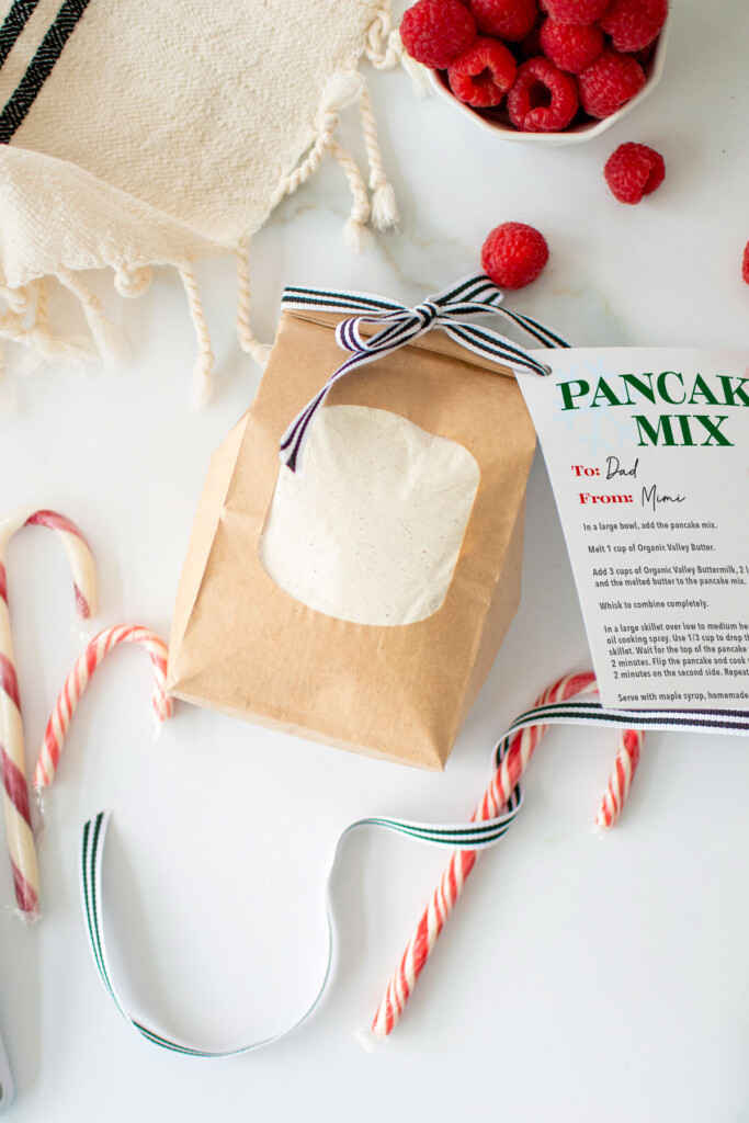small brown bag of homemade pancake mix with a ribbon on a white marble counter.