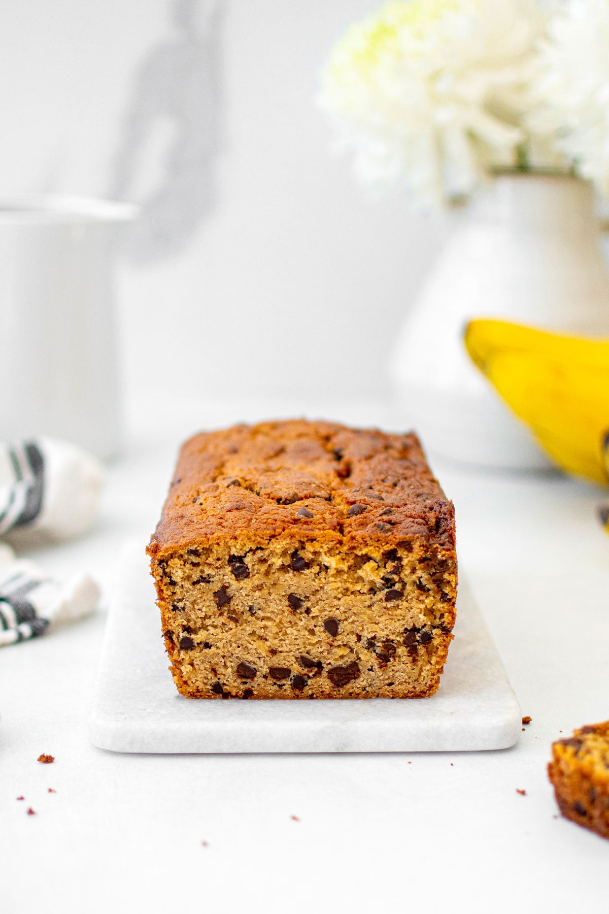 eggless mini chocolate chip banana bread sliced on a white marble board.