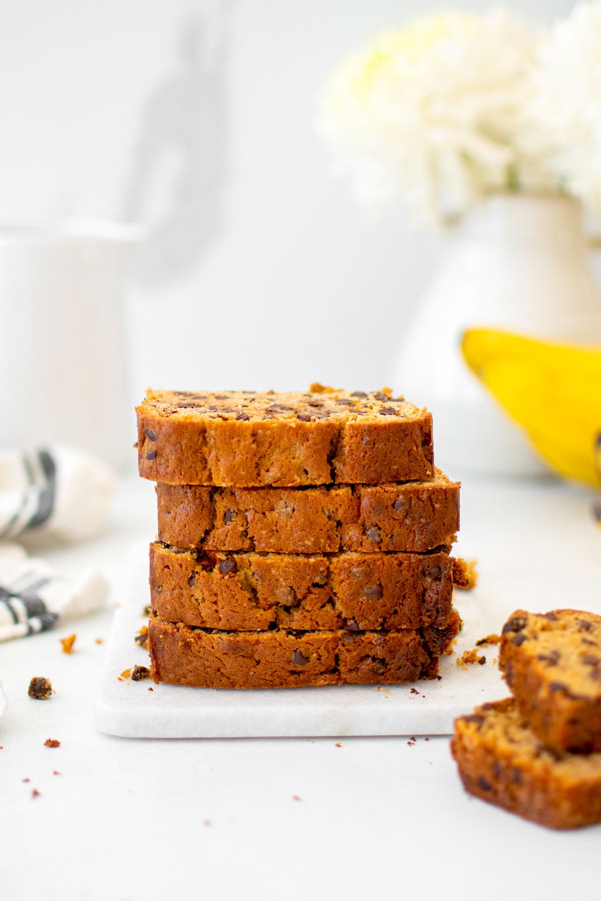 stack of eggless mini chocolate chip banana bread sliced on a white marble board.