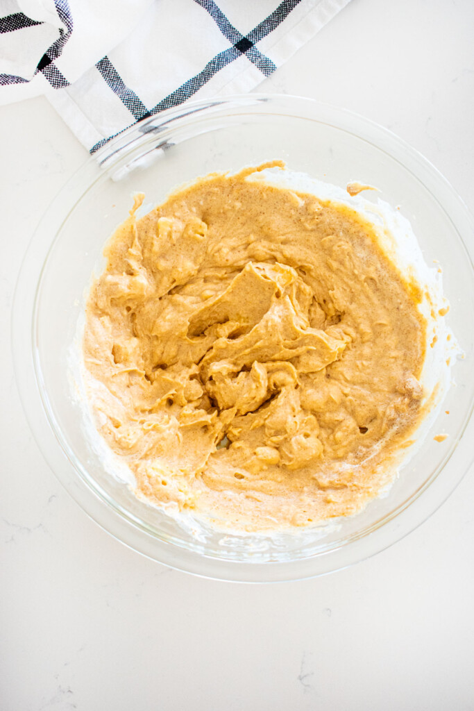 wet ingredients for eggless banana bread mixed together in a glass mixing bowl on a marble counter.