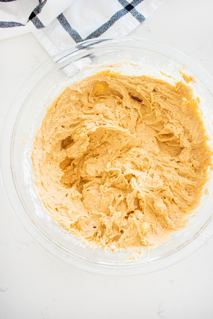 eggless banana bread batter in a glass mixing bowl on a marble counter.