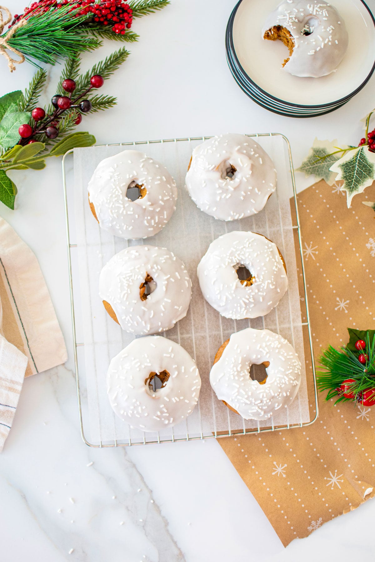 frosted gingerbread baked donuts on a cooling rack on a white marble counter.