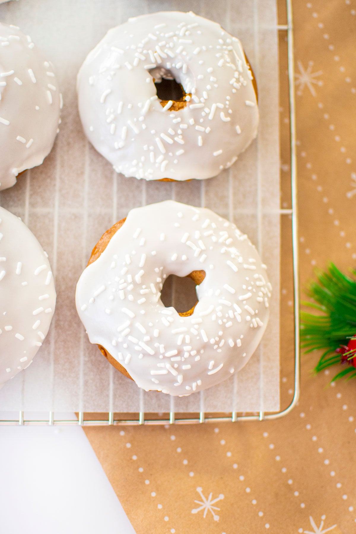 frosted gingerbread baked donuts on a cooling rack on a white marble counter.