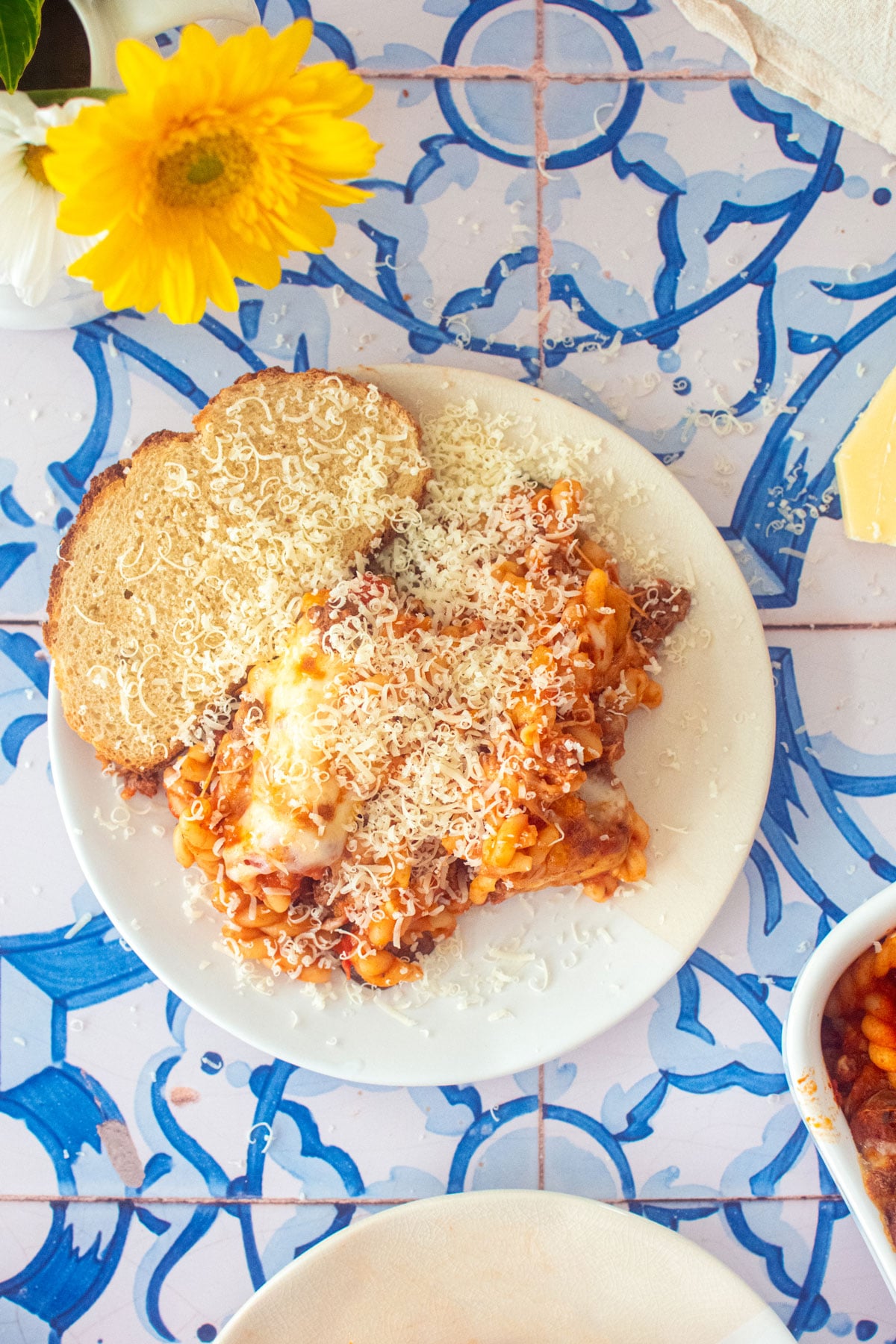 mushroom zucchini baked pasta on a plate with sourdough bread and parmesan cheese.