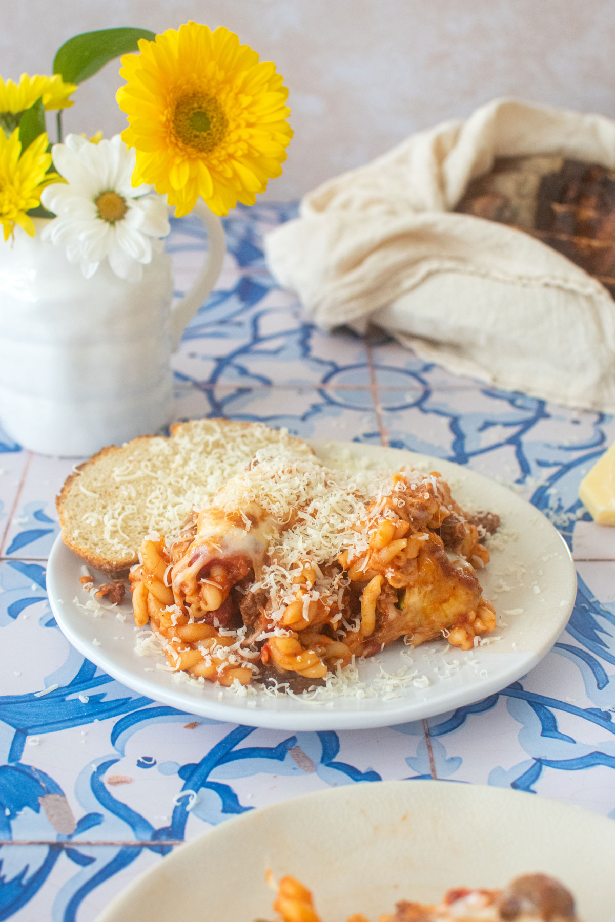 mushroom zucchini baked pasta on a plate with sourdough bread and parmesan cheese.