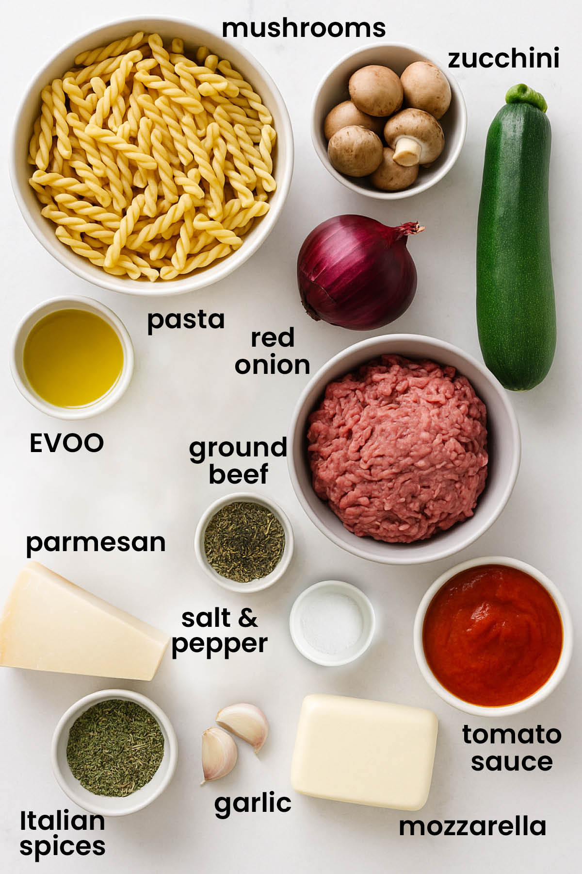individual ingredients for mushroom zucchini baked pasta laid out against a white background.