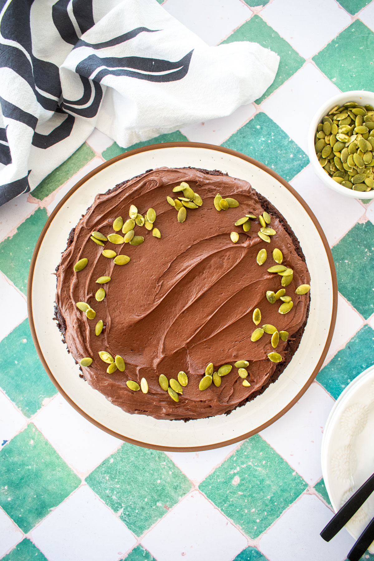 pumpkin spice chocolate zucchini cake on a green tile counter on a white palte.