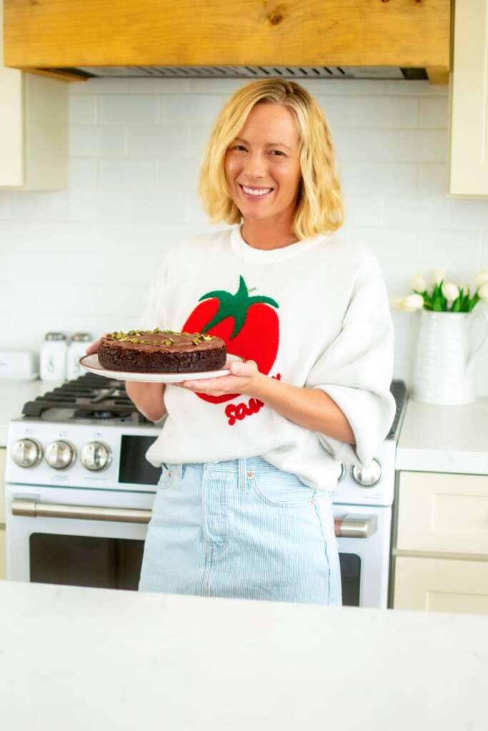 woman holding a pumpkin spice chocolate zucchini cake in the kitchen.