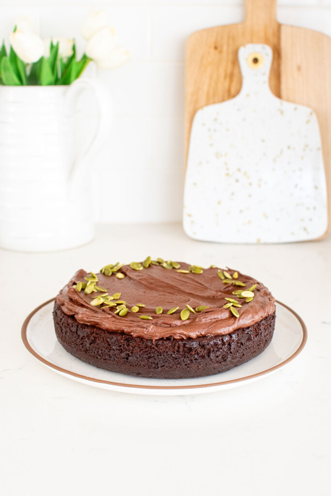 pumpkin spice chocolate zucchini cake on a white plate on a white marble countertop.