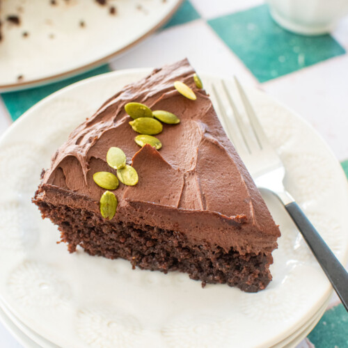 slice of pumpkin spice chocolate zucchini cake without eggs on a white plate with a fork.
