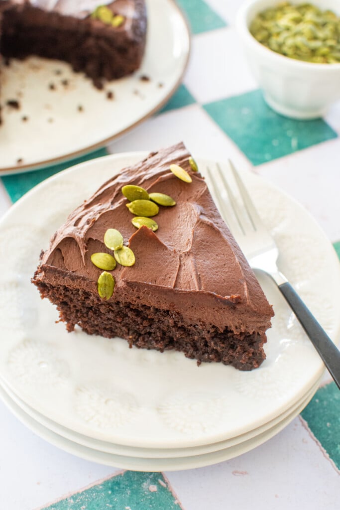 slice of pumpkin spice chocolate zucchini cake without eggs on a white plate with a fork.