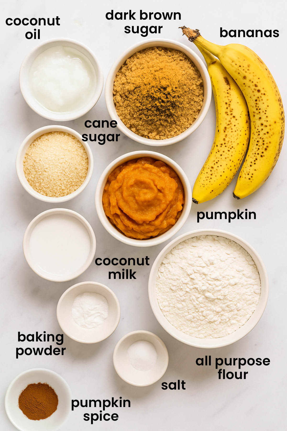 individual ingredients for vegan pumpkin spice banana bread laid out against a white background.