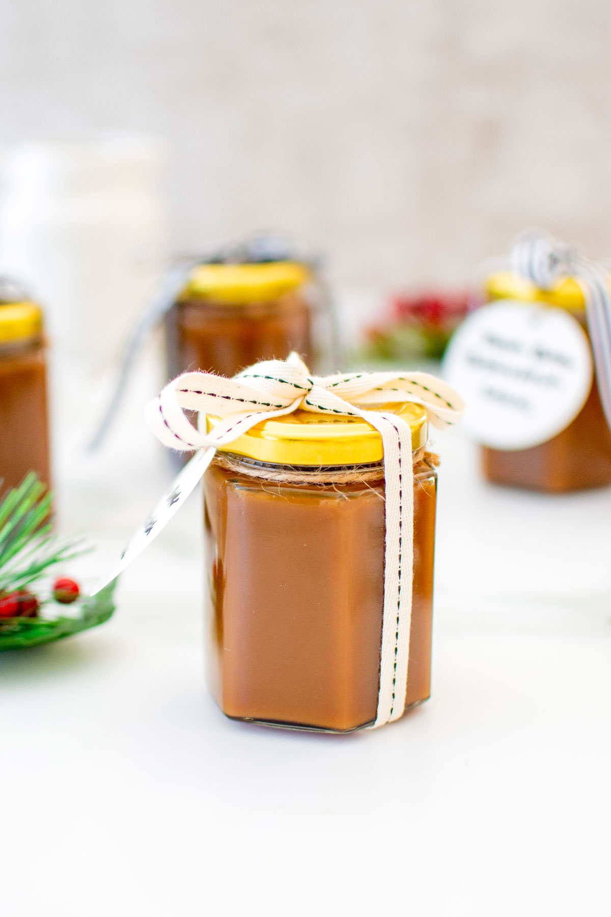brown butter butterscotch sauce in a glass jar with a ribbon on a white marble counter.
